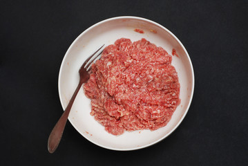 Fresh Raw Minced Beef Meat in a Bowl on Black Table. top view. Food Process.