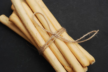 Pile of Italian Grissini on Black Background with sea salt and spice. Close up breadsticks on dark background. Grissini top view.