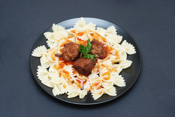 Meat Balls and Farfalle Pasta on Black plate, Dark Toned Blue background