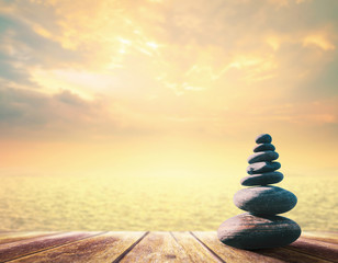 World philosophy day concept: Zen stones on wooden table over gold sea and sky background.