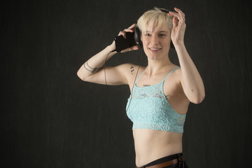 Young blonde woman in blue camisole dancing with headphones on.