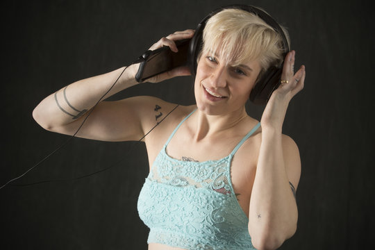 Happy young blonde woman dancing with headphones on.