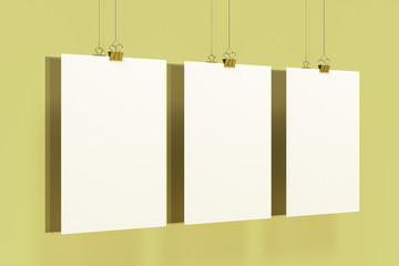 Three blank white posters with binder clip mockup on yellow background