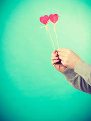 Male hand with little hearts on sticks.
