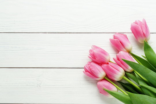 a bouquet of pink tulips on a white wooden background. top view. copy space. Holiday concept.