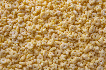 Background of cornflakes in the form of rings and stars, closeup.