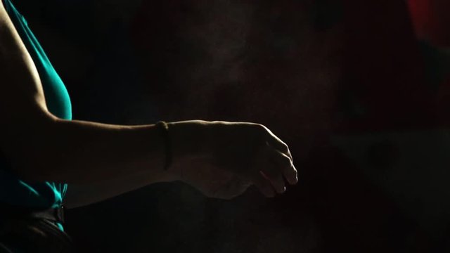 Close-up on a black background with a hand of a professional balder. Apply chalk on your hands against slipping. Cotton and dust scattered in different directions.