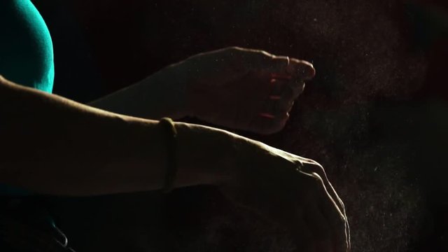 Close-up on a black background with a hand of a professional balder. Apply chalk on your hands against slipping. Cotton and dust scattered in different directions. Sport competitions.
