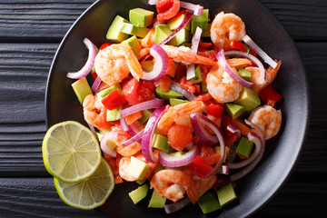 Spicy shrimp ceviche with vegetable salsa close-up on a plate. horizontal top view
