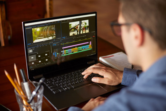 Freelancer video editor works at the laptop computer with movie editing sofware. Videographer vlogger or blogger camera man at work editing vlog. Tracking and revealing shot