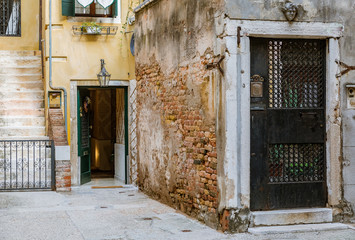 Fototapeta na wymiar Old courtyard with ornate gate on a narrow street in Venice Italy