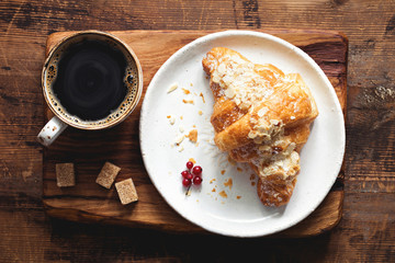Croissant and cup of coffee espresso on old wooden table. Top view. Breakfast concept