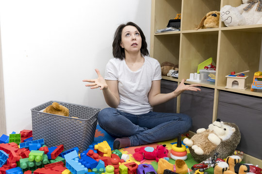 Young Mother Cleaning Her Kid's Toys At Home. Woman Tired After Work. Organization Toy