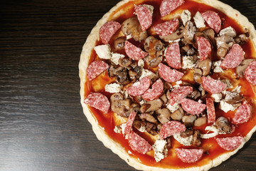 pizza cooking, meat of chiken, sausage salami, thick dough,  pizza crust, pizza is on a dark table, pizza with chicken and sausage salami, cooking process, mushrooms,  Champignon