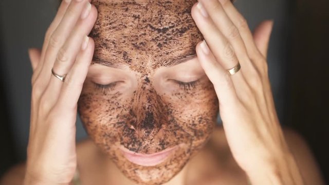 Closeup face of woman with facial coffee mask - video in slow motion