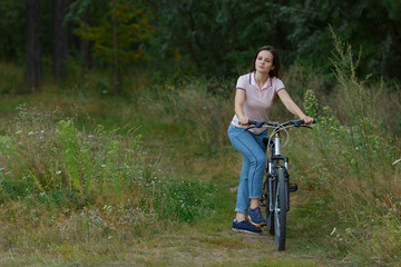 Fototapeta na wymiar Happy beautiful girl riding on bicycle in the forest.