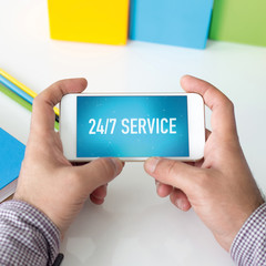Man holding smartphone which displaying 24/7 Service