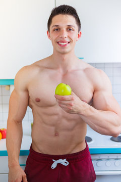 Gesunde Ernährung junger Bodybuilder Mann Essen Apfel Frucht Obst in der Küche Hochformat