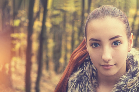 Cute beautiful pretty redhead female teenager in autumn forest. Close up charming portrait, shallow depth of field, toned.