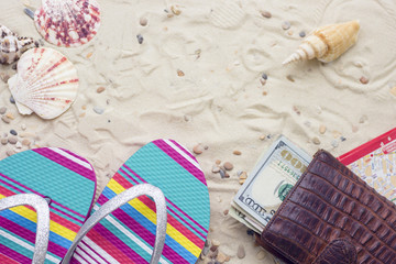 Enjoying vacation mood, beach sneakers and money purse on white sand background. Top view, closeup.