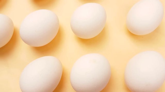 White easter eggs on pastel yellow background close up macro.