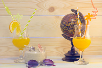 Enjoying vacation planning mood, globe, swimming glasses and coctail on white sand background. Instagram