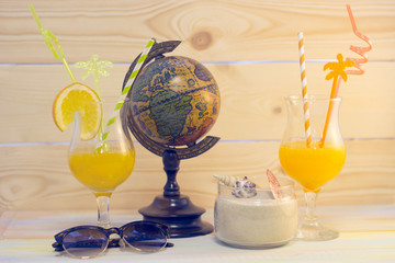 Enjoying vacation planning mood, globe and coctail on white sand background. Instagram