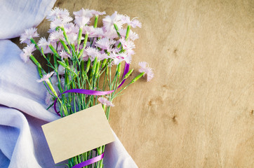 Delicate flowers and empty greeting card.
