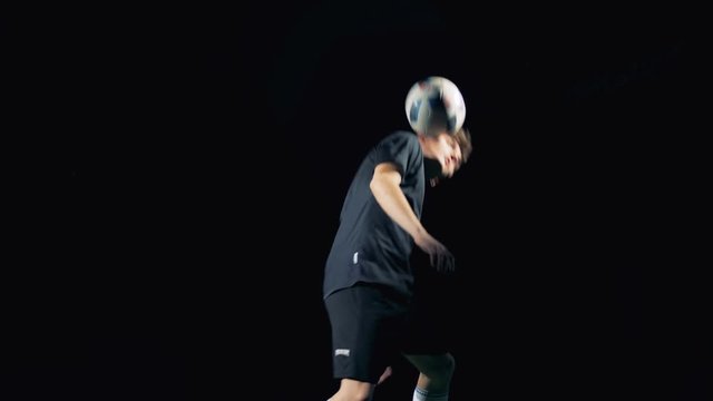 Soccer player playing with a football ball making tricks. Slow motion.