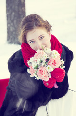 Bride at the wedding in winter in a white dress and a red scarf in red mittens, wrapped in uggs 