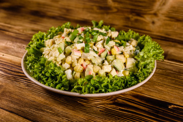 Ceramic plate with salad from crab sticks on wooden table
