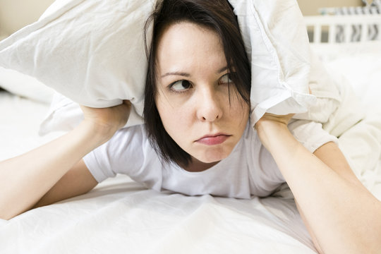 Troubled Woman In Bed Covering Ears To Shut Out Noise