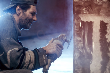 Closeup of a worker who processes granite using a grinding machine.