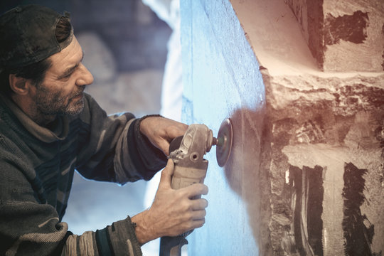 Closeup of a worker who processes granite using a grinding machine.
