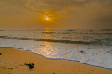 Golden Sunrise and glistening white sea foam on shore at Koh Samui