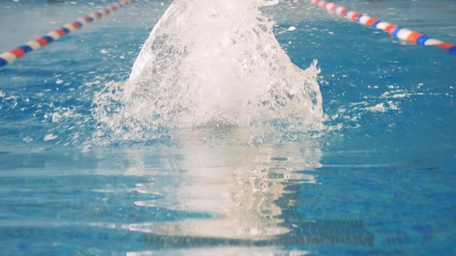 A front view on a swimmer in goggles moving in butterfly style. 