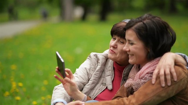 Happy Family at the Picnic in the Park Using Mobile Phone to Take Phote of Themselves. Adult Daughter with Her Mother are Taking Selfie by Smartphone Outdoors.