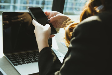 businesswoman holding mobile phone texting message at office. young female entrepreneur using smartphone at cafe. freelance woman working with cellphone at coffee shop. business concept