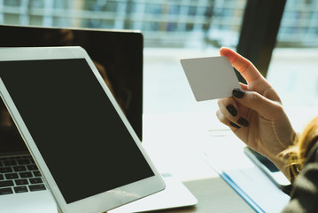 woman holding a credit card and using tablet for online shopping at cafe. businesswoman purchase goods from internet at office. female adult make payment on bank website at workplace