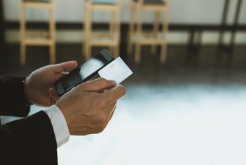 man holding a credit card and using smart phone for online shopping at cafe. businessman purchase goods from internet at office. male adult make payment on bank website at workplace
