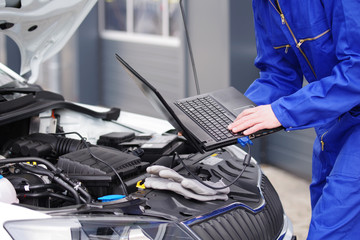 Fototapeta Mechaniker arbeitet mit einem Laptop an einem Auto, Motorsteuerung  obraz