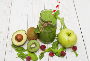 healthy green smoothie with banana, spinach, avocado and kiwi in a glass bottles on a rustic