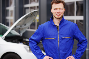 Automechaniker sympathisch lächelnd inspiziert einen Motor 