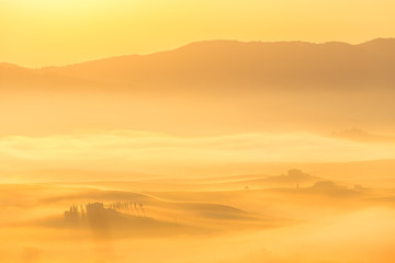 Enchanting golden foggy sunrise in Tuscany, Italy