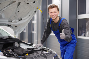 Automechaniker sympathisch lächelnd inspiziert einen Motor 