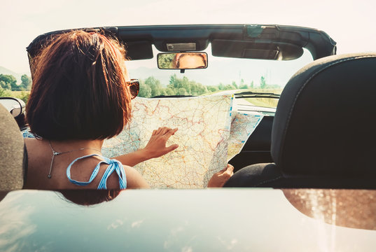 Woman reads roads map sitting in cabriolet car