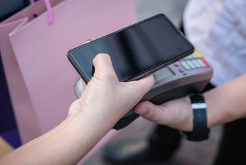 woman use smartphone to make mobile payment with electronic reader. customer paying with near field communication, NFC technology. people use app for online shopping.