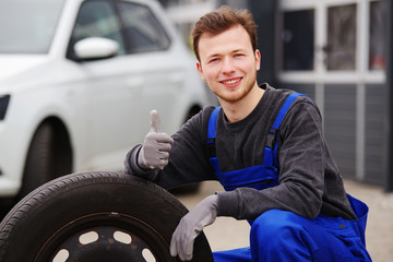Mechaniker mit einem Auto-Reifen, Radwechsel 