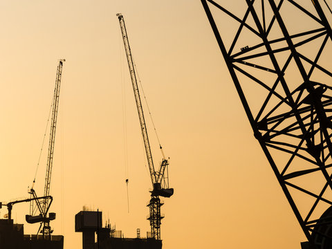Cranes working on Building Construction site sunset sky Silhouette Industrial background