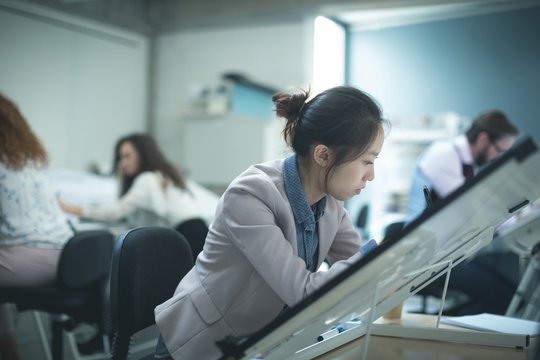Female executive working over drafting table